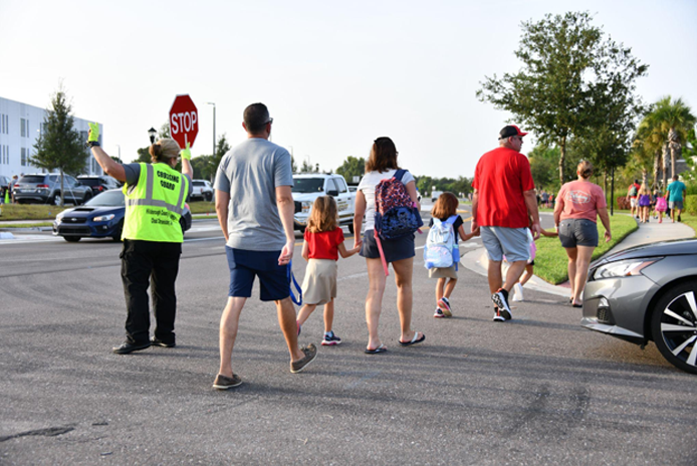 crossing guard assisting families cross street at crosswalk