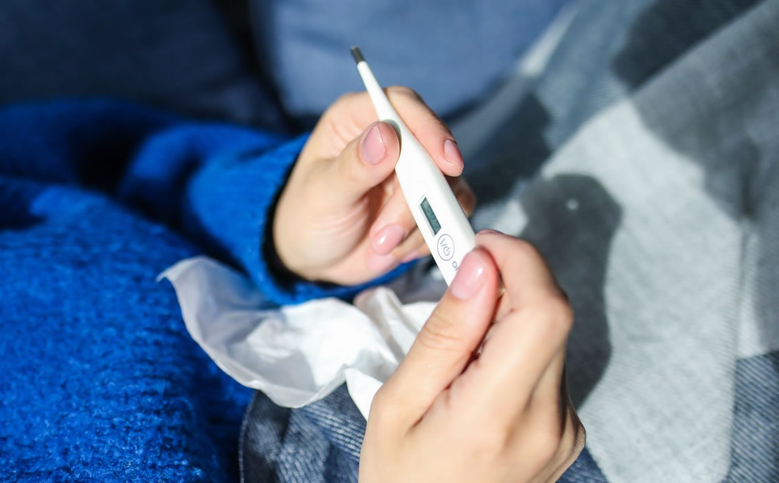 Image of person holding a thermometer